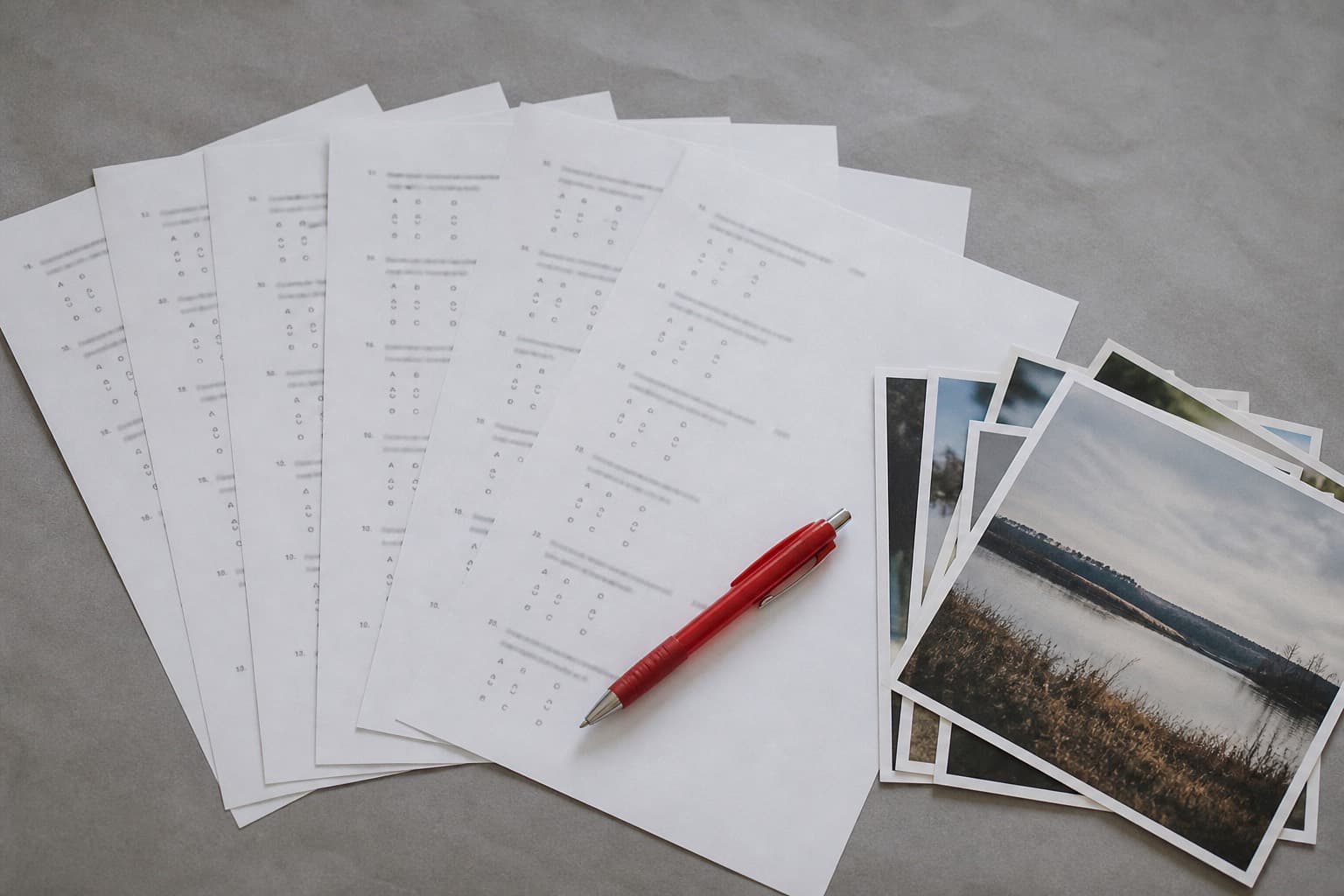Printed quiz sheets and photo prints on a desk with a red pen