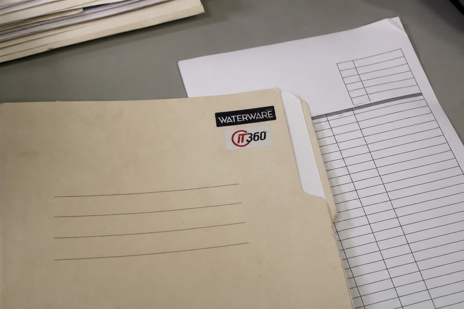 Invoice folder with Waterware and IT360 marks on a paper desk