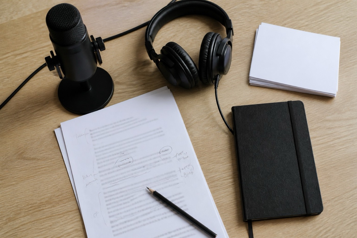 Microphone, headphones, and a marked script on a desk